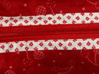 Red fabric pouch with white zipper and pattern on a light gray background