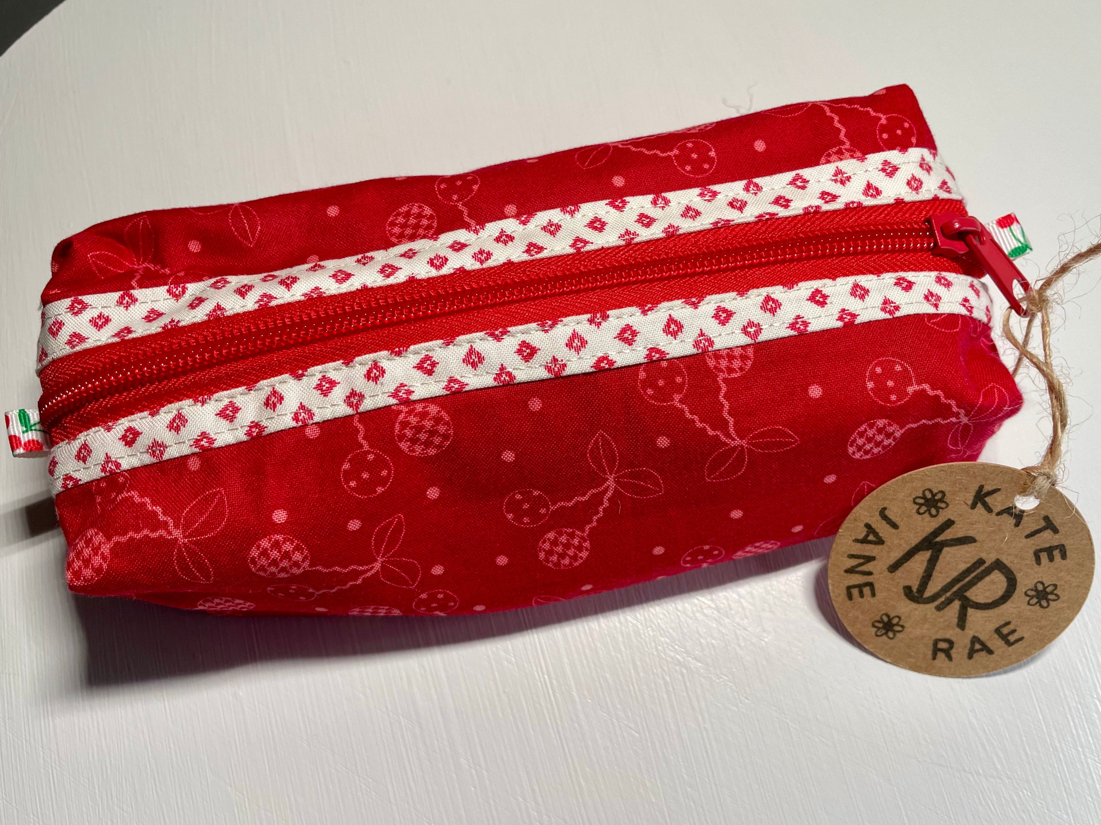 Red and white patterned pouch with a visible brand tag on a light background