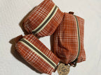 Three brown plaid pouches with zippers on a white background