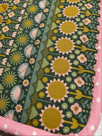 Fabric with sunflower pattern on a green background, bordered by pink fabric.
