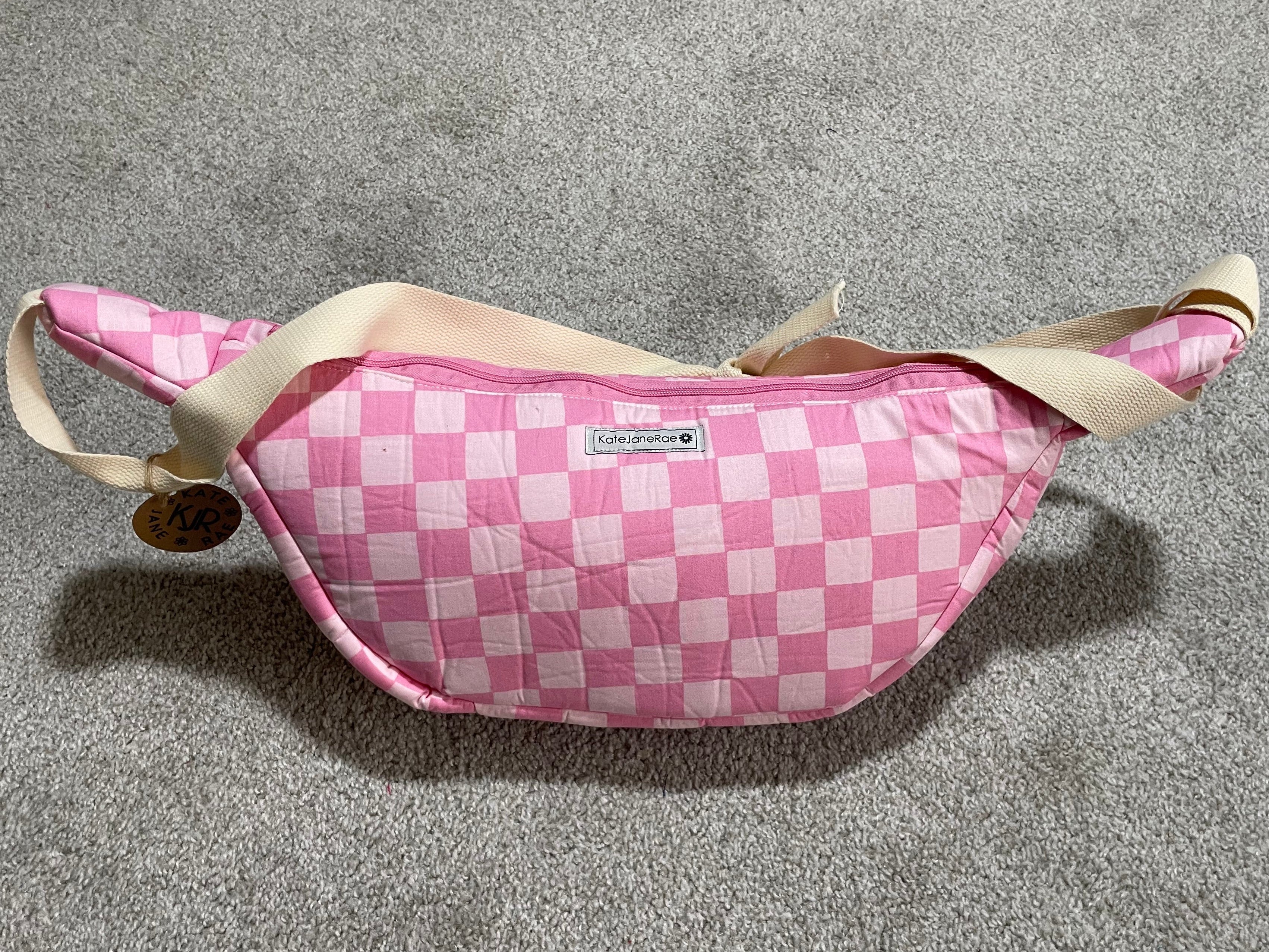 Pink checkered fanny pack on a gray surface