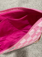 Pink bag with a checkered pattern on a gray carpet