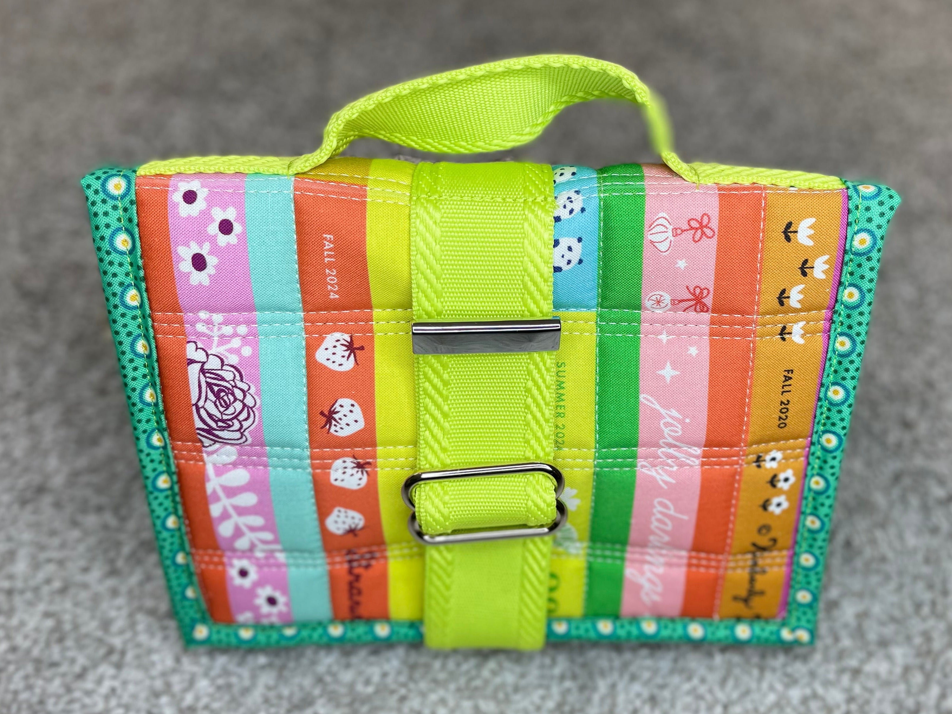 Colorful striped wallet with a green strap on a gray surface