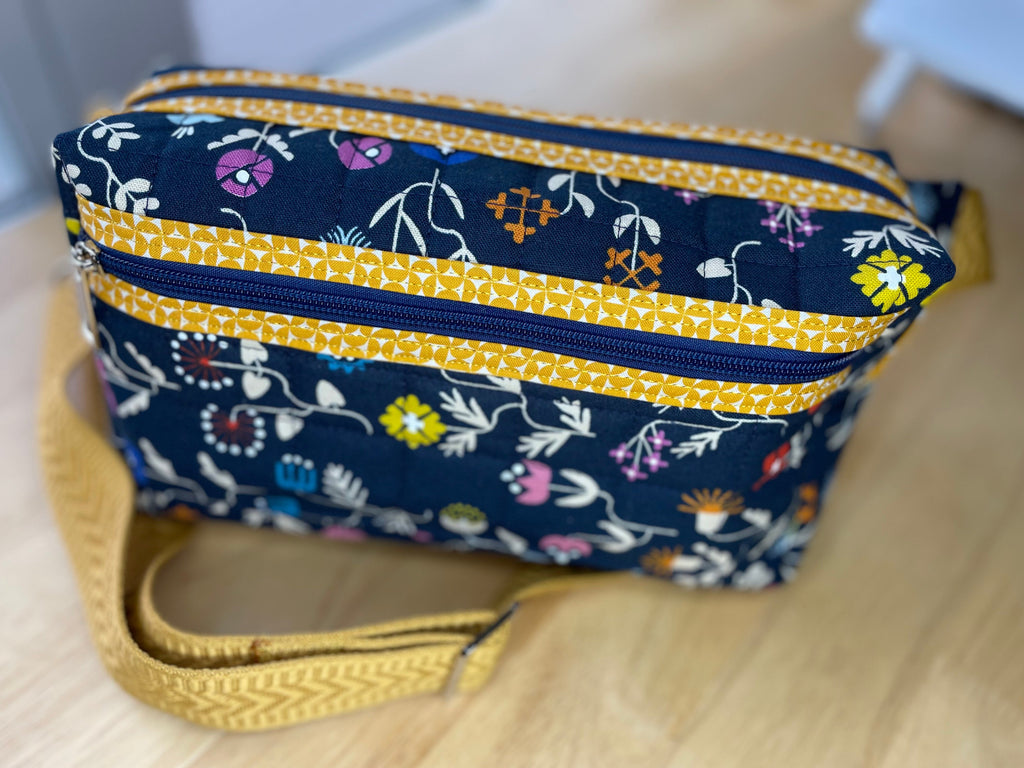 Navy blue pouch with floral pattern and yellow accents on a wooden surface