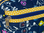 Floral-patterned bag with a yellow strap on a wooden surface