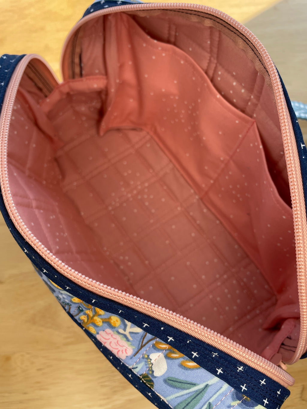 Floral-patterned bag with a pink interior on a wooden surface