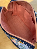 Floral-patterned bag with a pink interior on a wooden surface