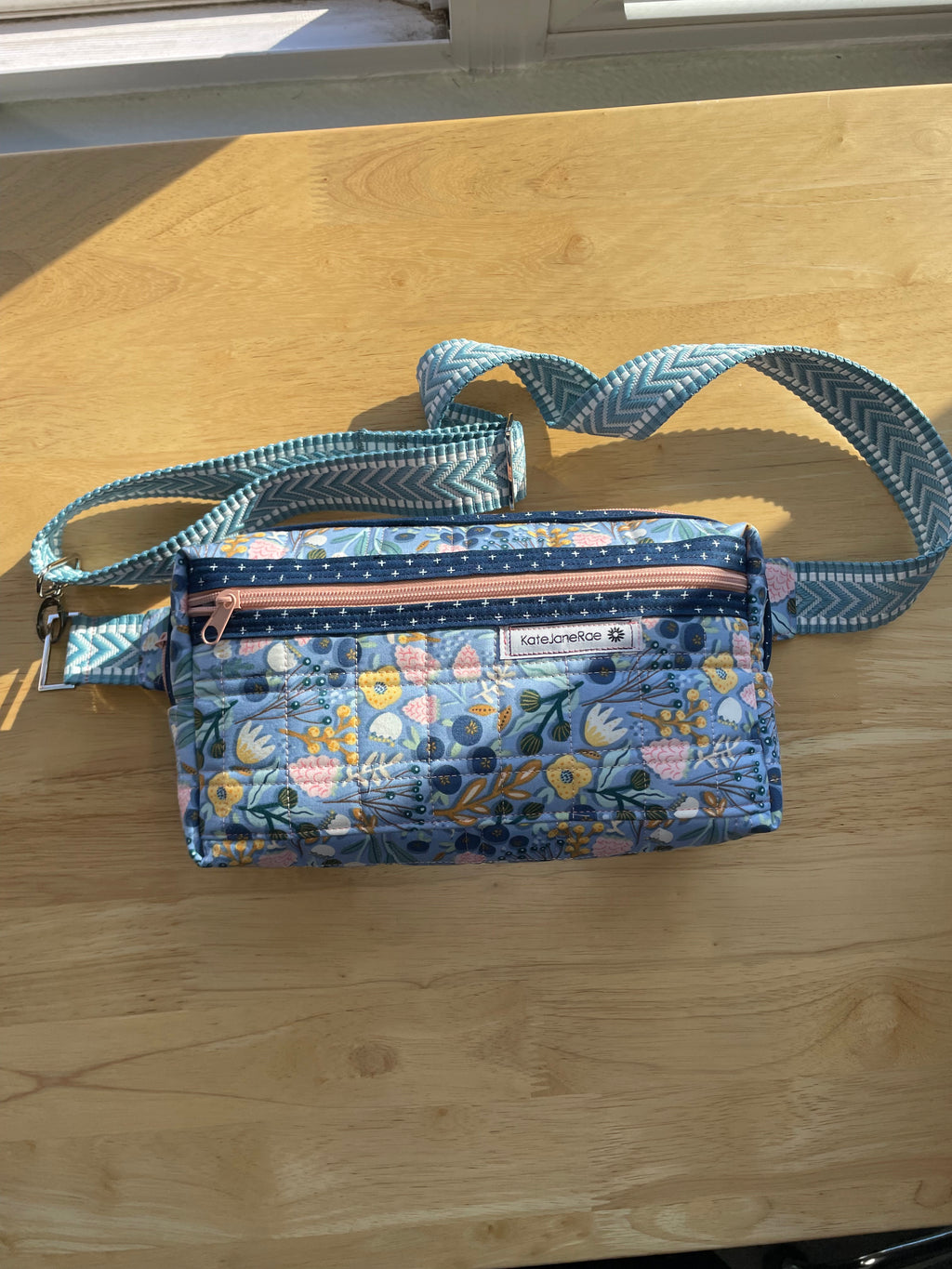 Floral-patterned bag with a strap on a wooden surface