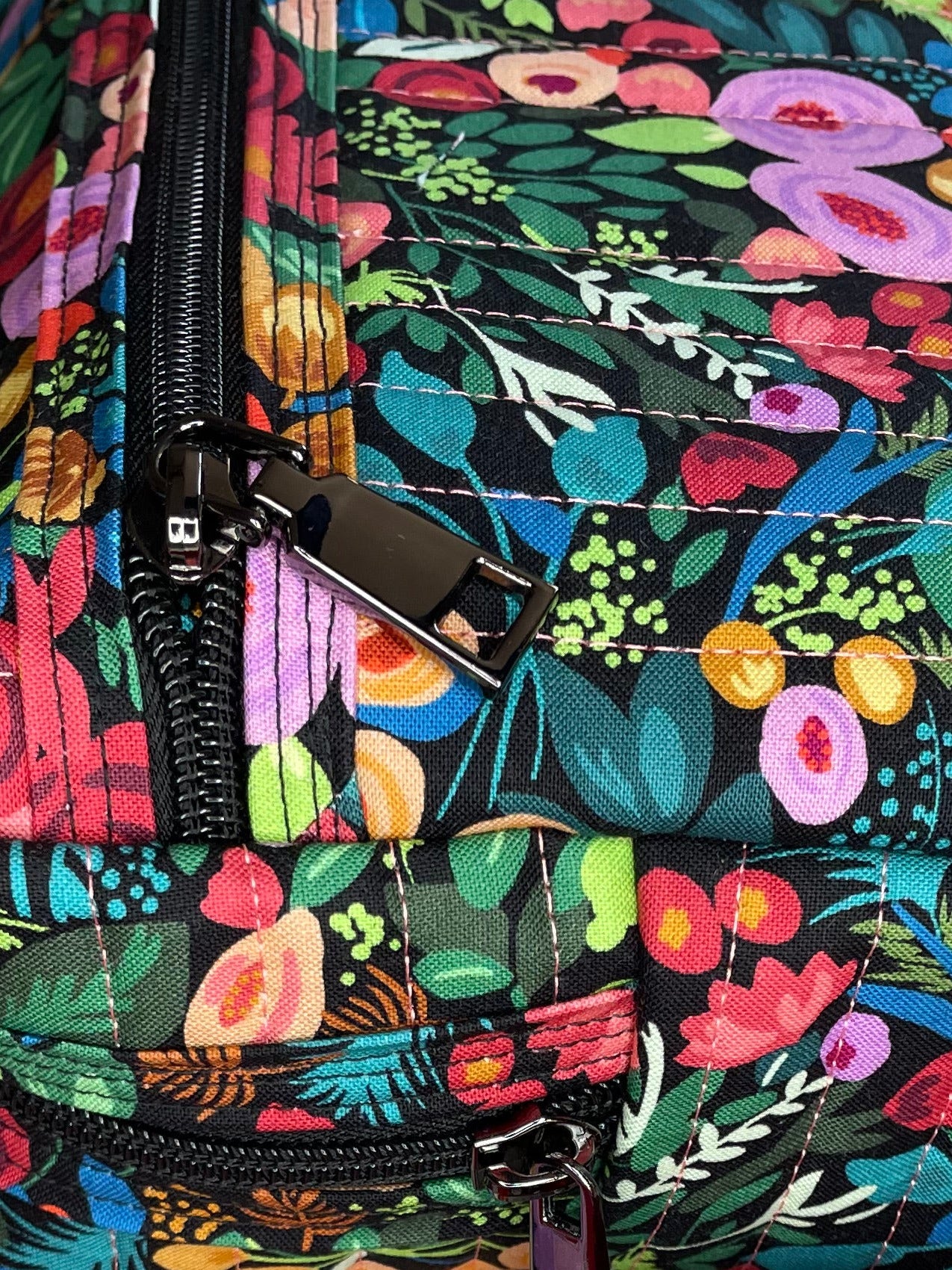 Colorful floral-patterned bag with a red strap on a gray surface