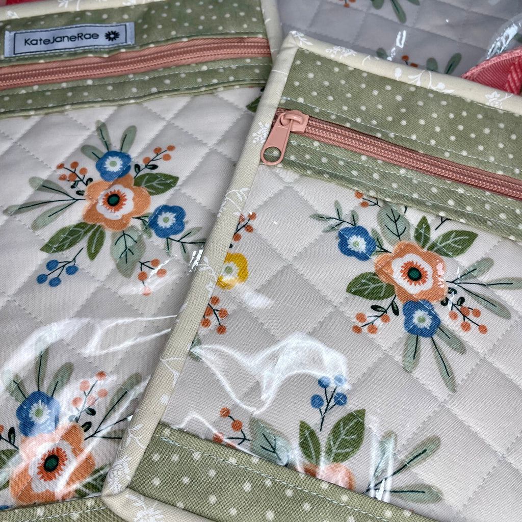 Floral-patterned pouches with zippers on a quilted surface
