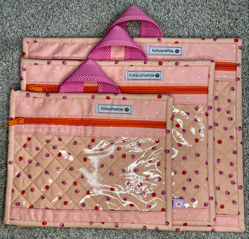 Set of three pink and beige bags with visible branding on a gray surface