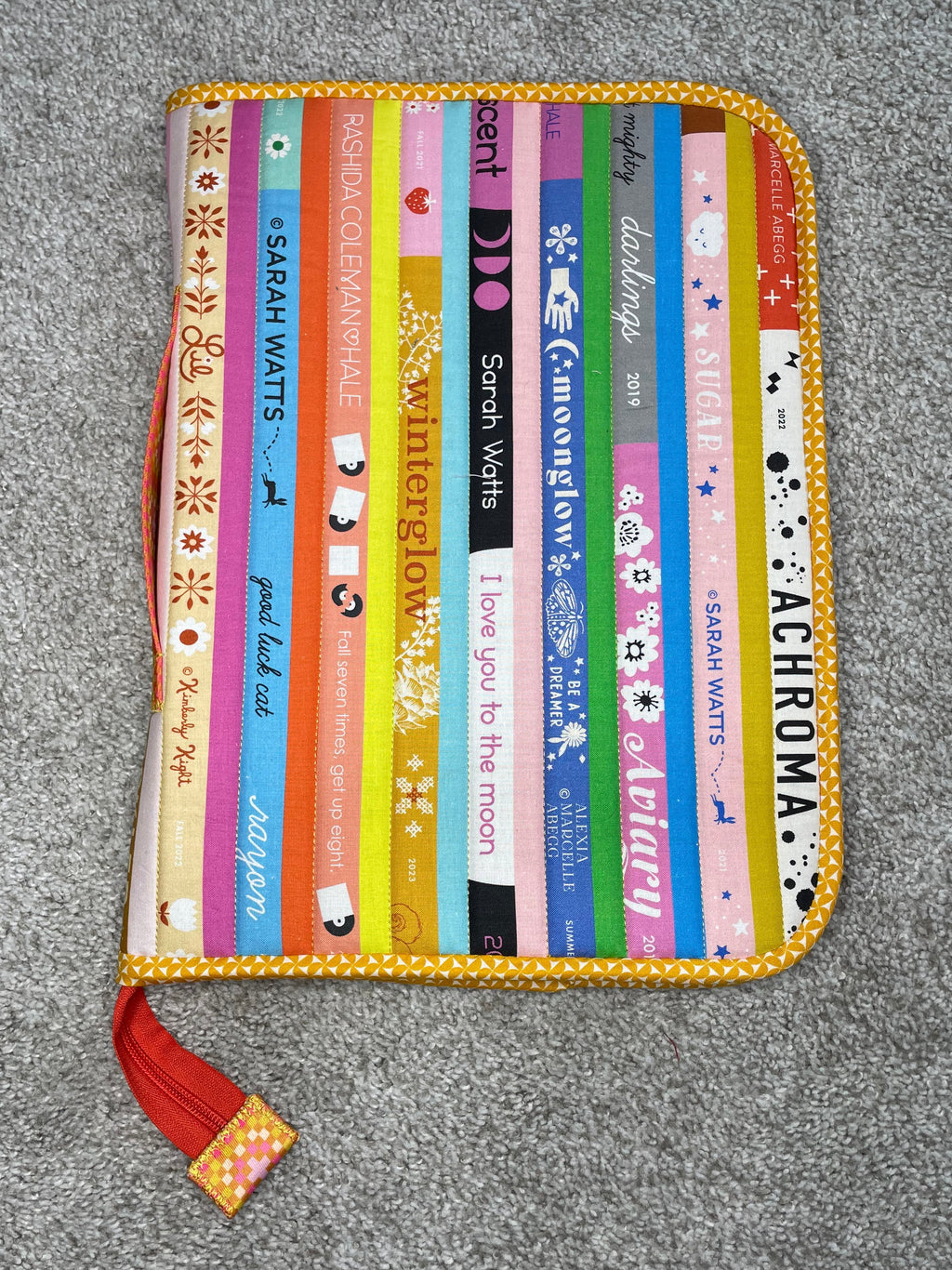 Colorful striped pouch with text on a gray surface