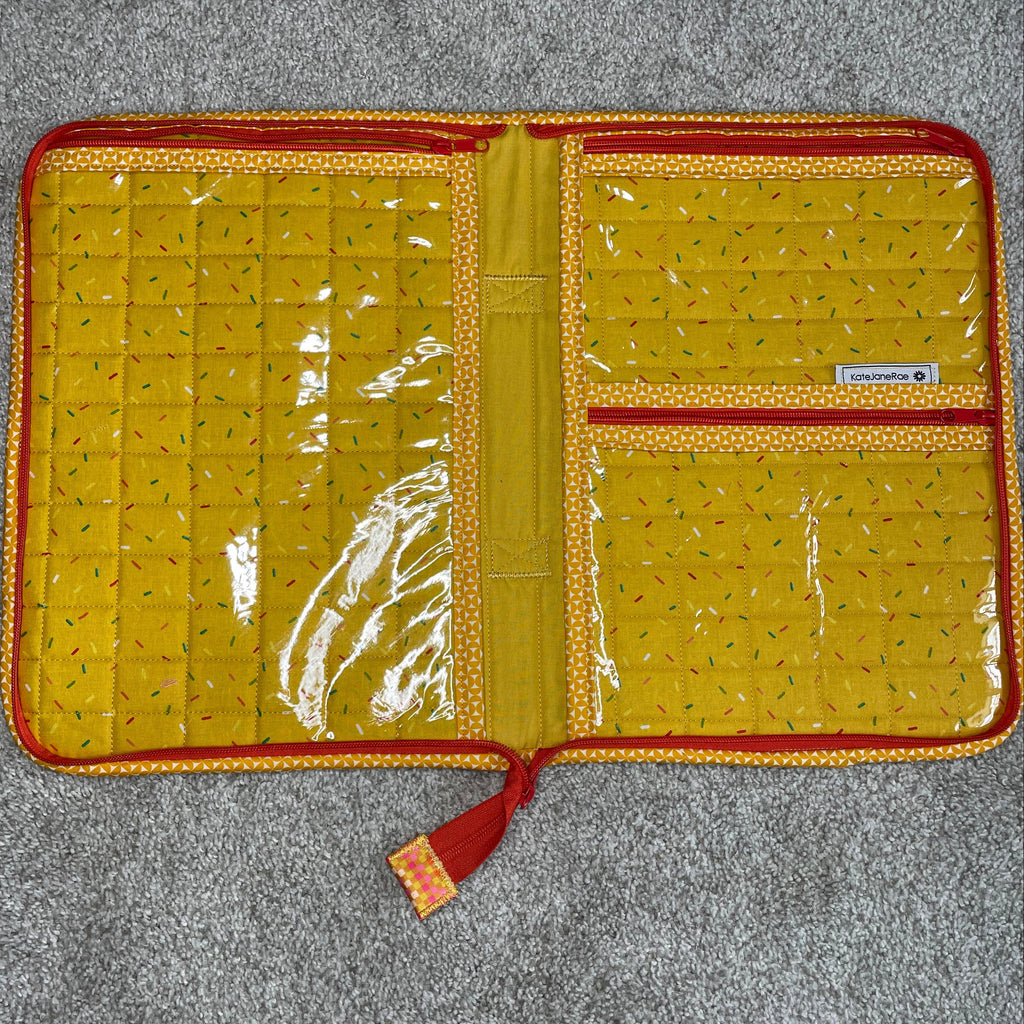 Yellow quilted wallet with red accents on a gray surface