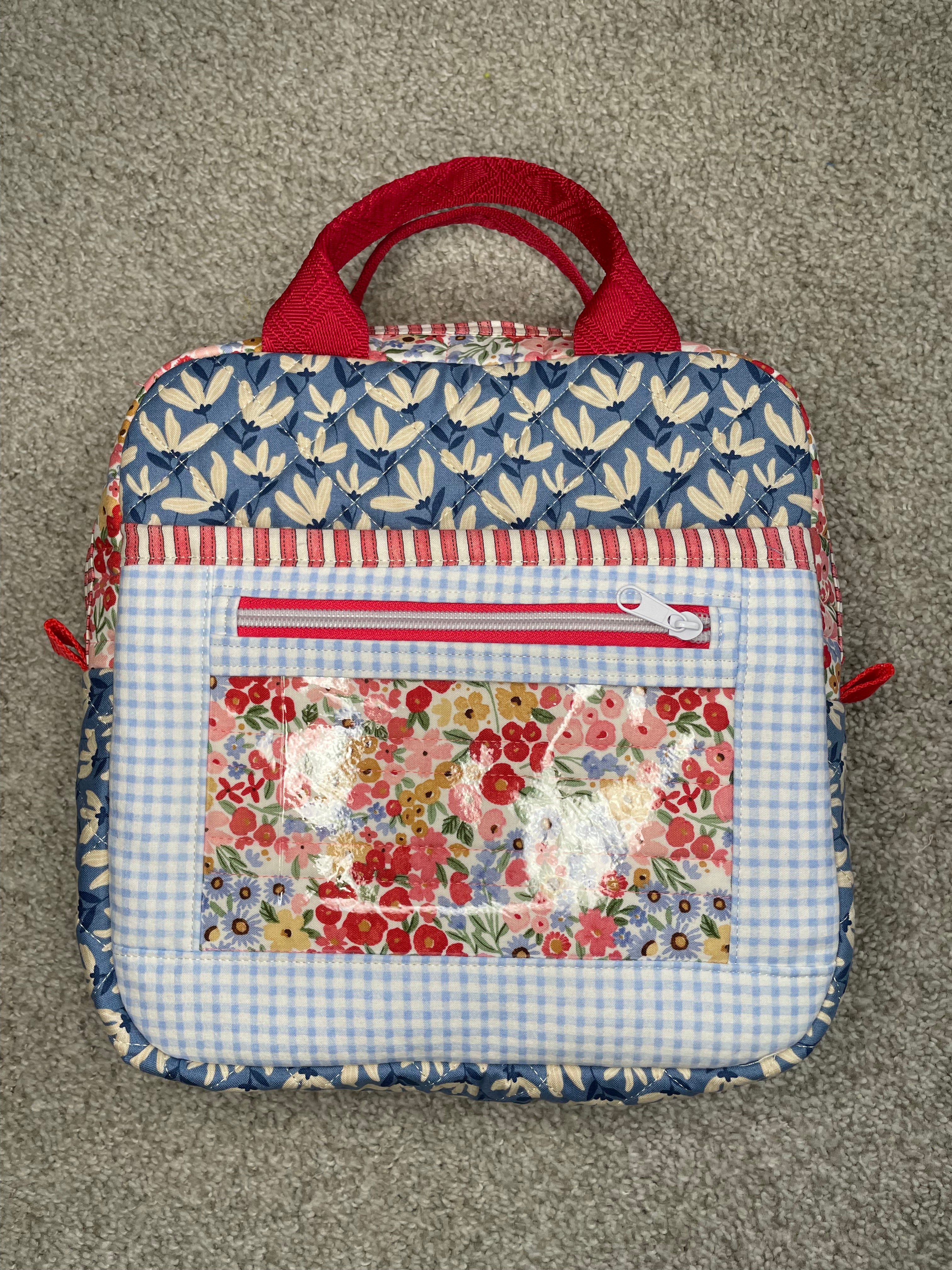 Fabric bag with floral and checkered patterns on a gray surface
