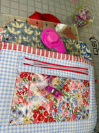 Fabric pouch with floral and checkered patterns on a cutting mat with scissors and clips.