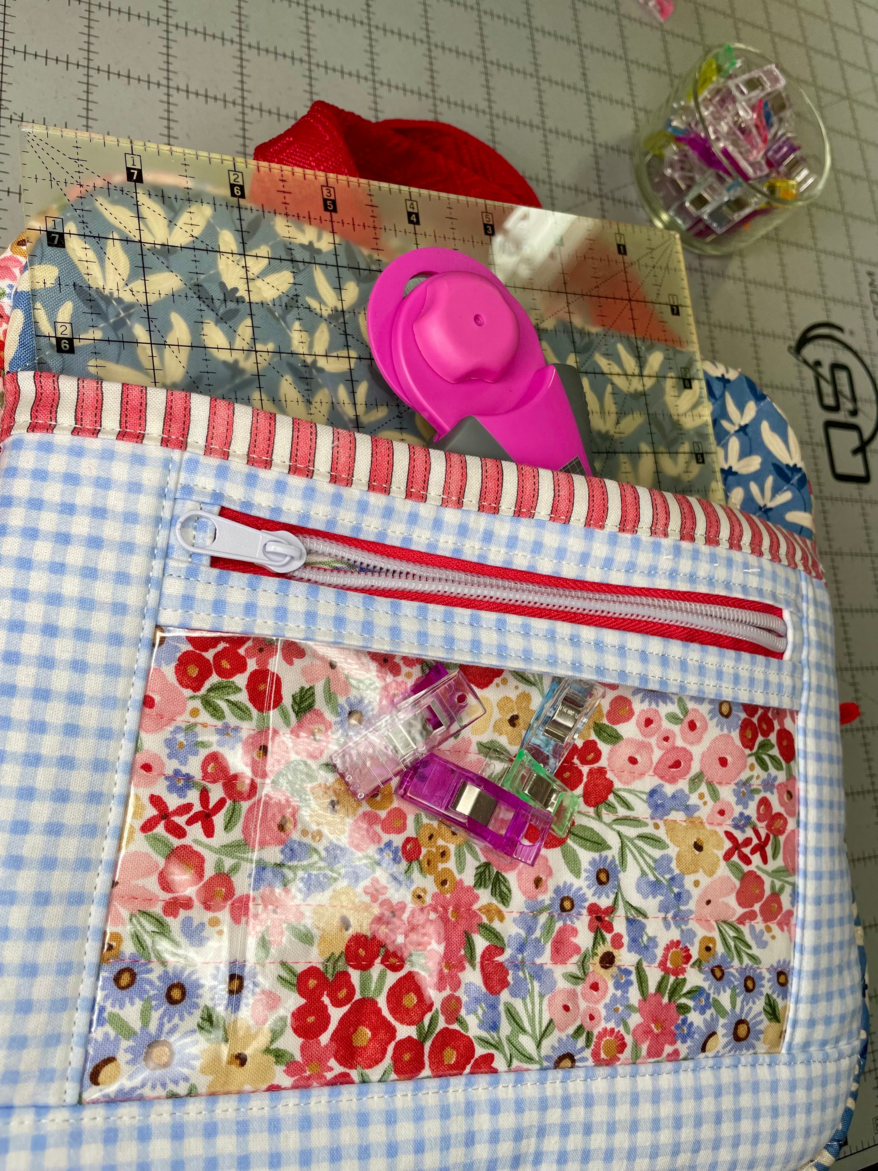 Fabric pouch with floral and checkered patterns on a cutting mat with scissors and clips.