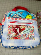 Fabric pouch with scissors and thread on a cutting mat