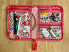 Pink floral travel case with stationery items on a wooden surface