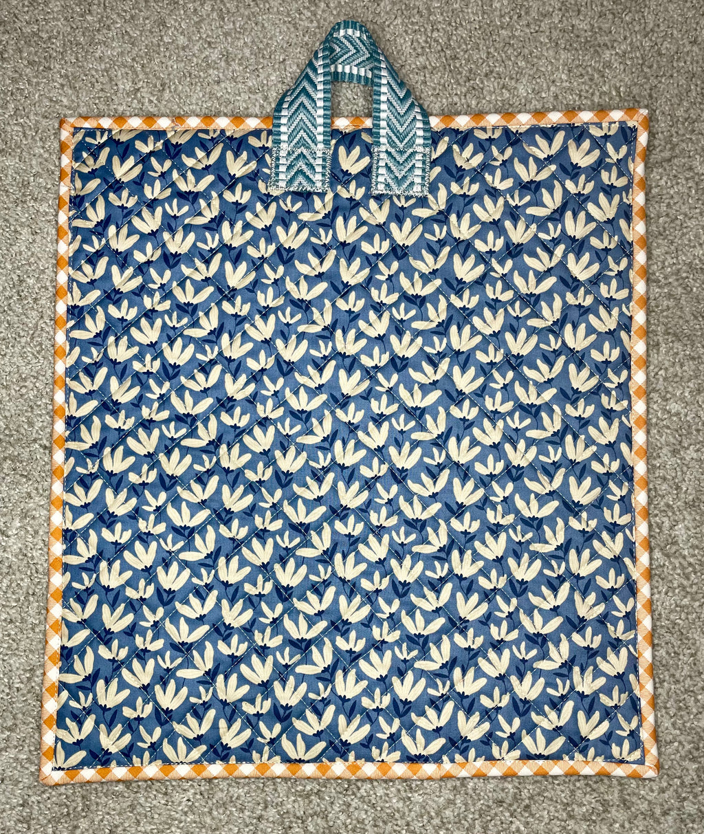 Blue and white patterned fabric with a handle on a gray surface