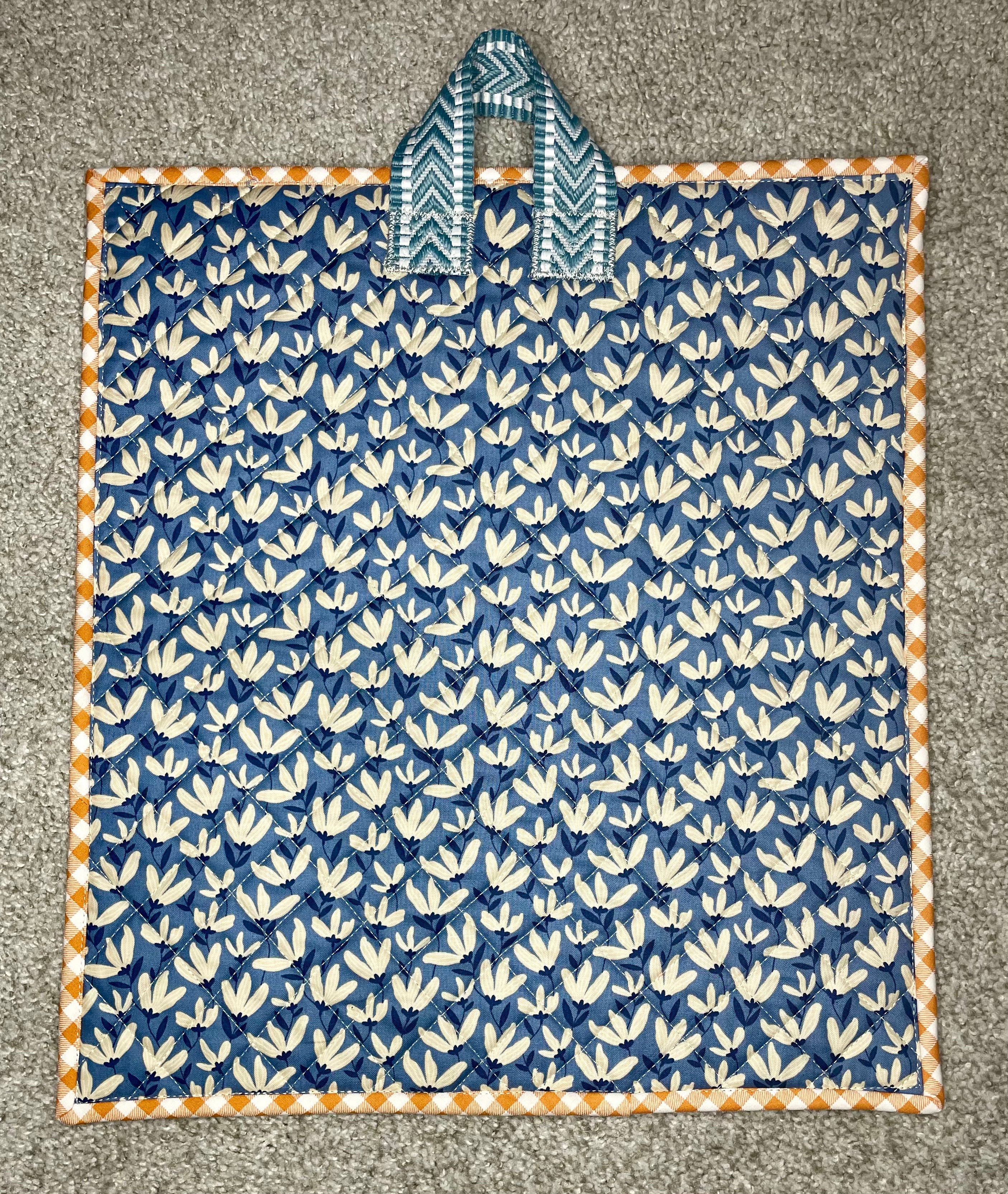 Blue and white patterned fabric with a handle on a gray surface