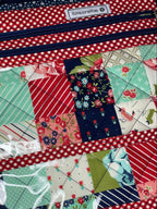 Patchwork quilt with red, blue, and green patterns on a gray surface