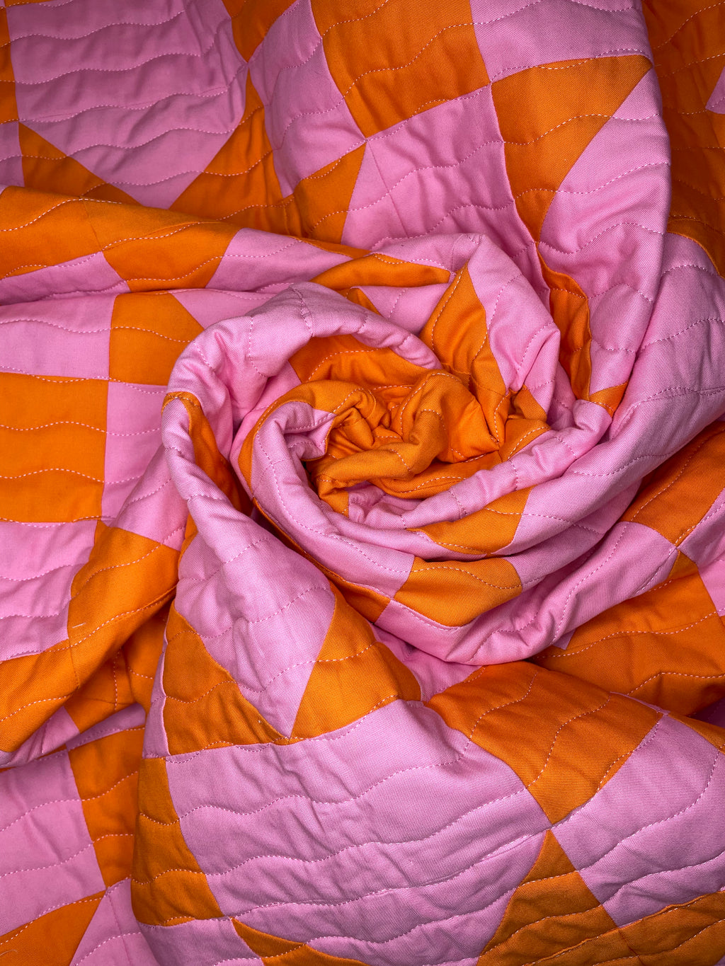 Pink and orange checkered quilt with a folded corner