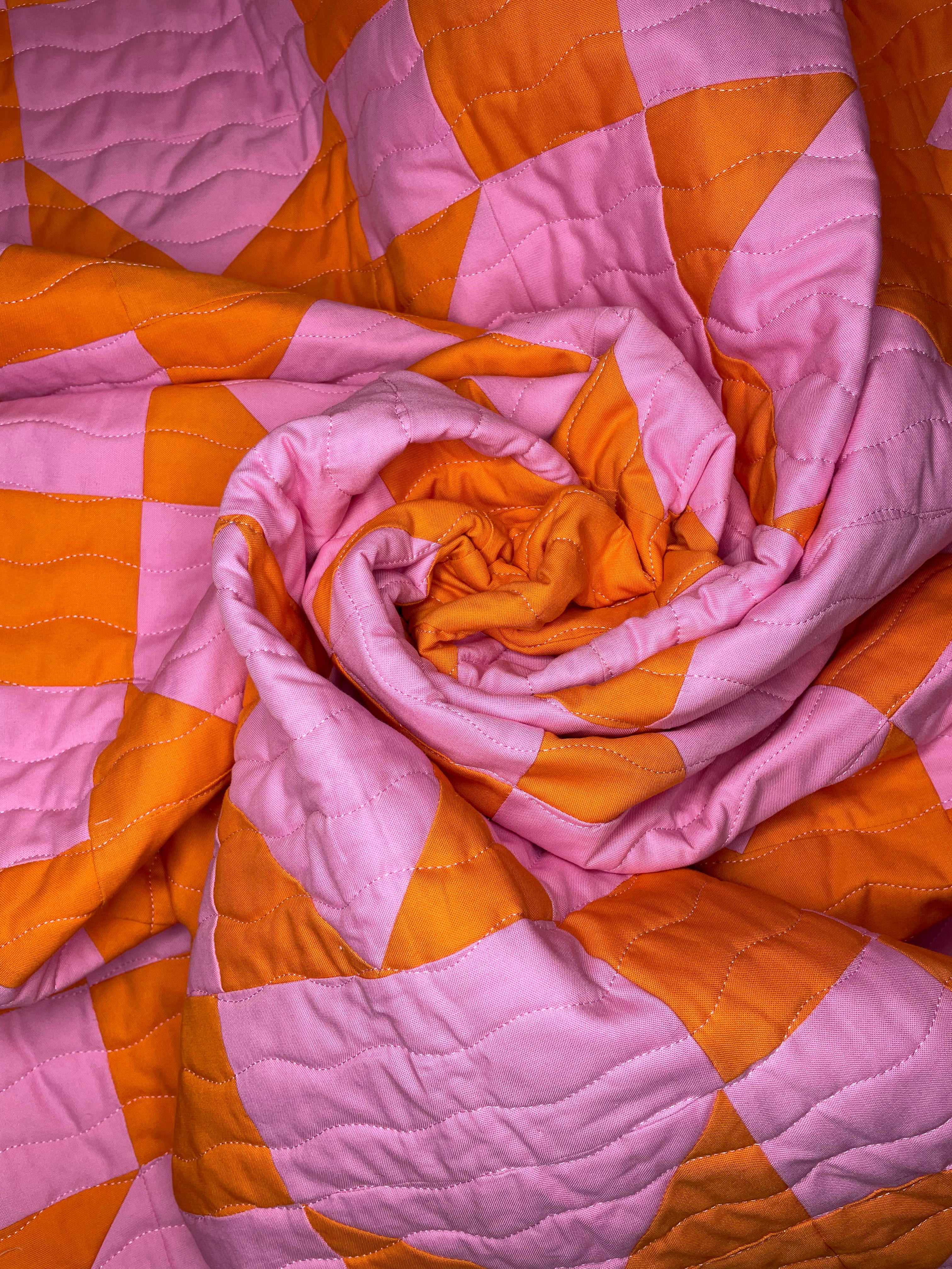Pink and orange checkered quilt with a folded corner
