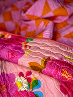 Close-up of a colorful quilt with floral patterns and geometric shapes.