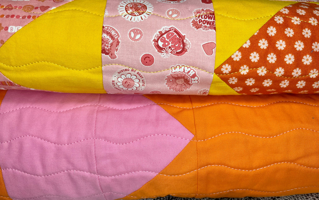 Colorful quilt with patchwork pattern featuring various shapes and colors.