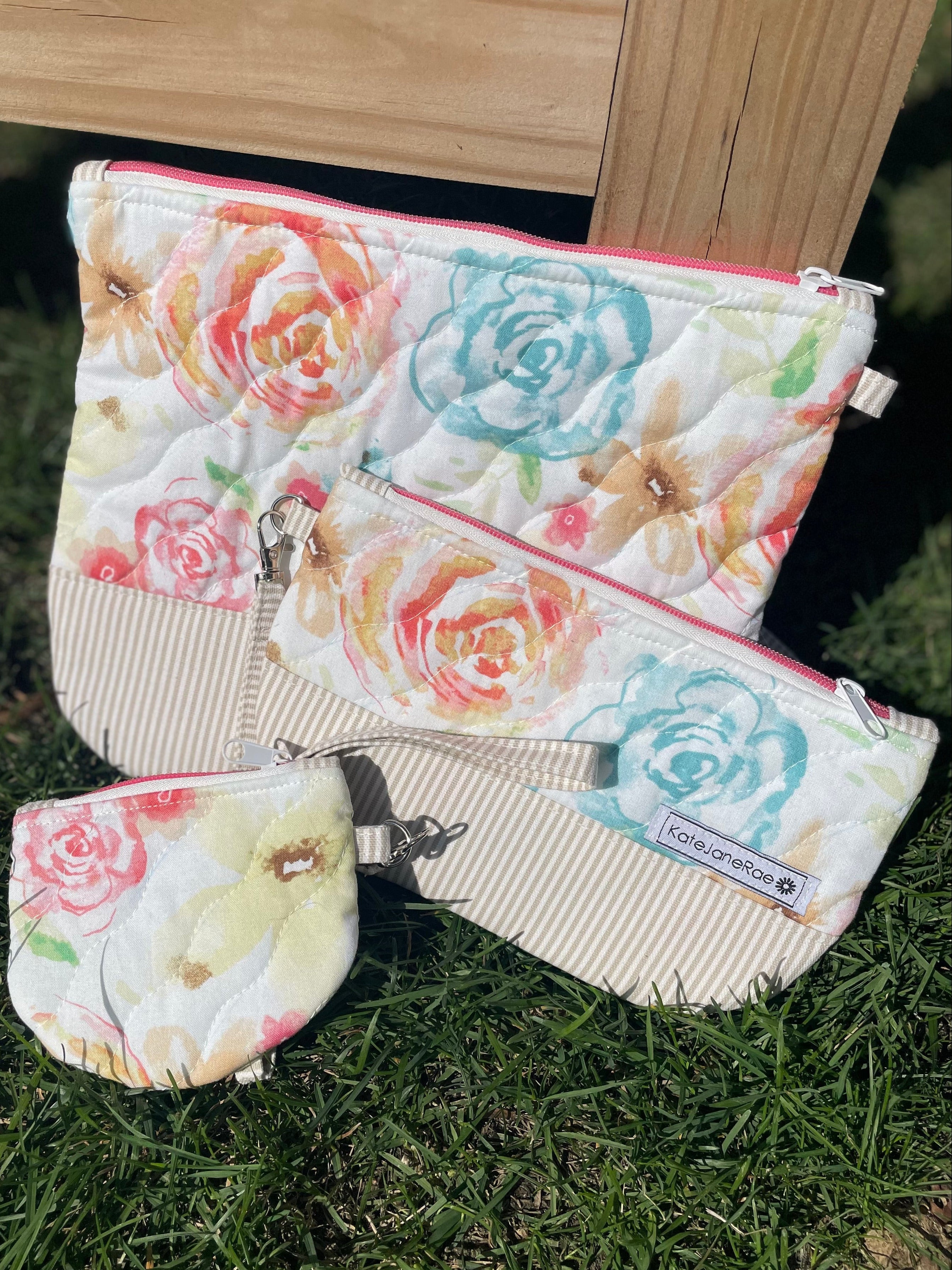 Floral-patterned pouches on grass with wooden background