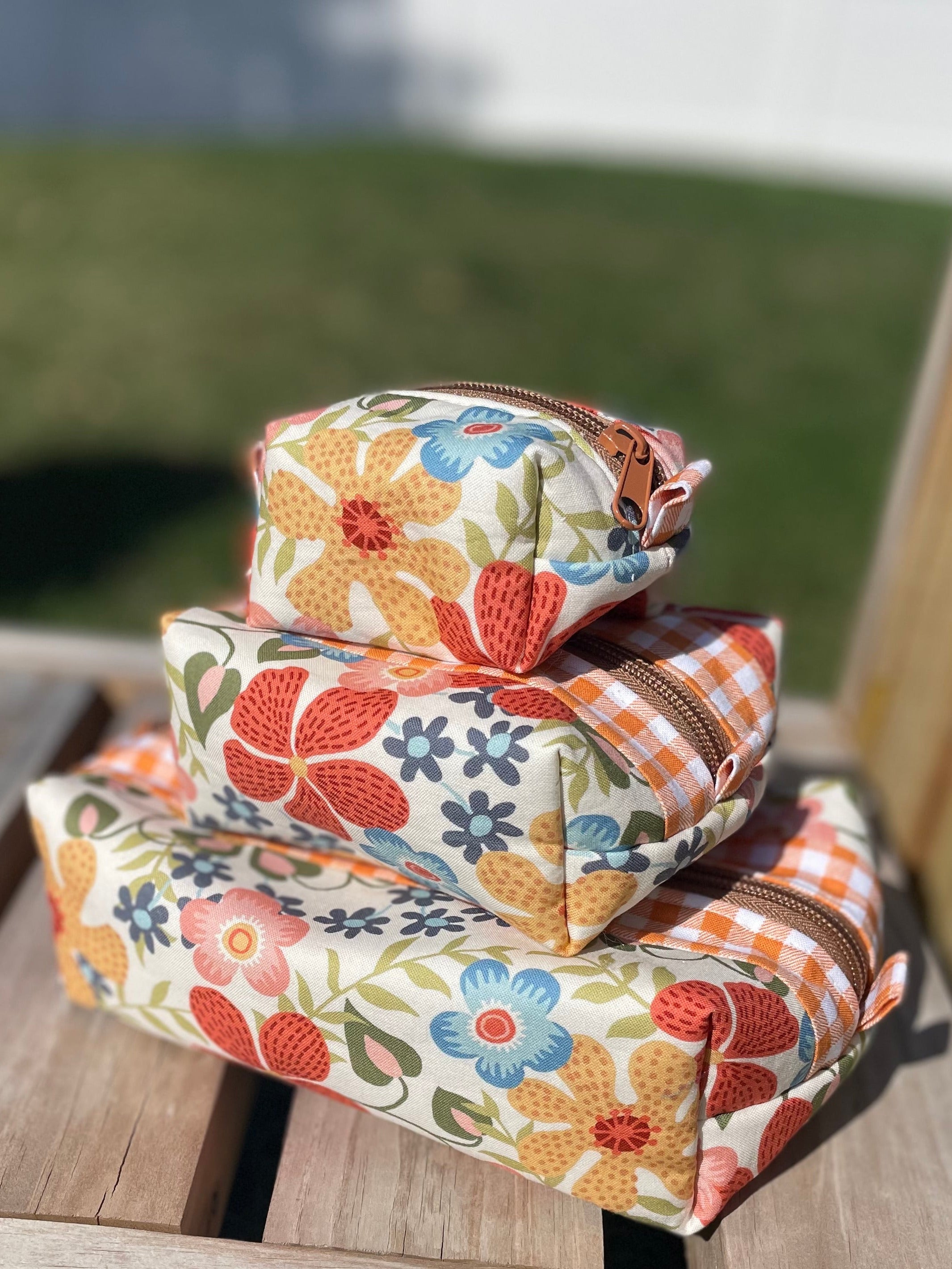 Stack of floral-patterned pouches on a wooden surface outdoors