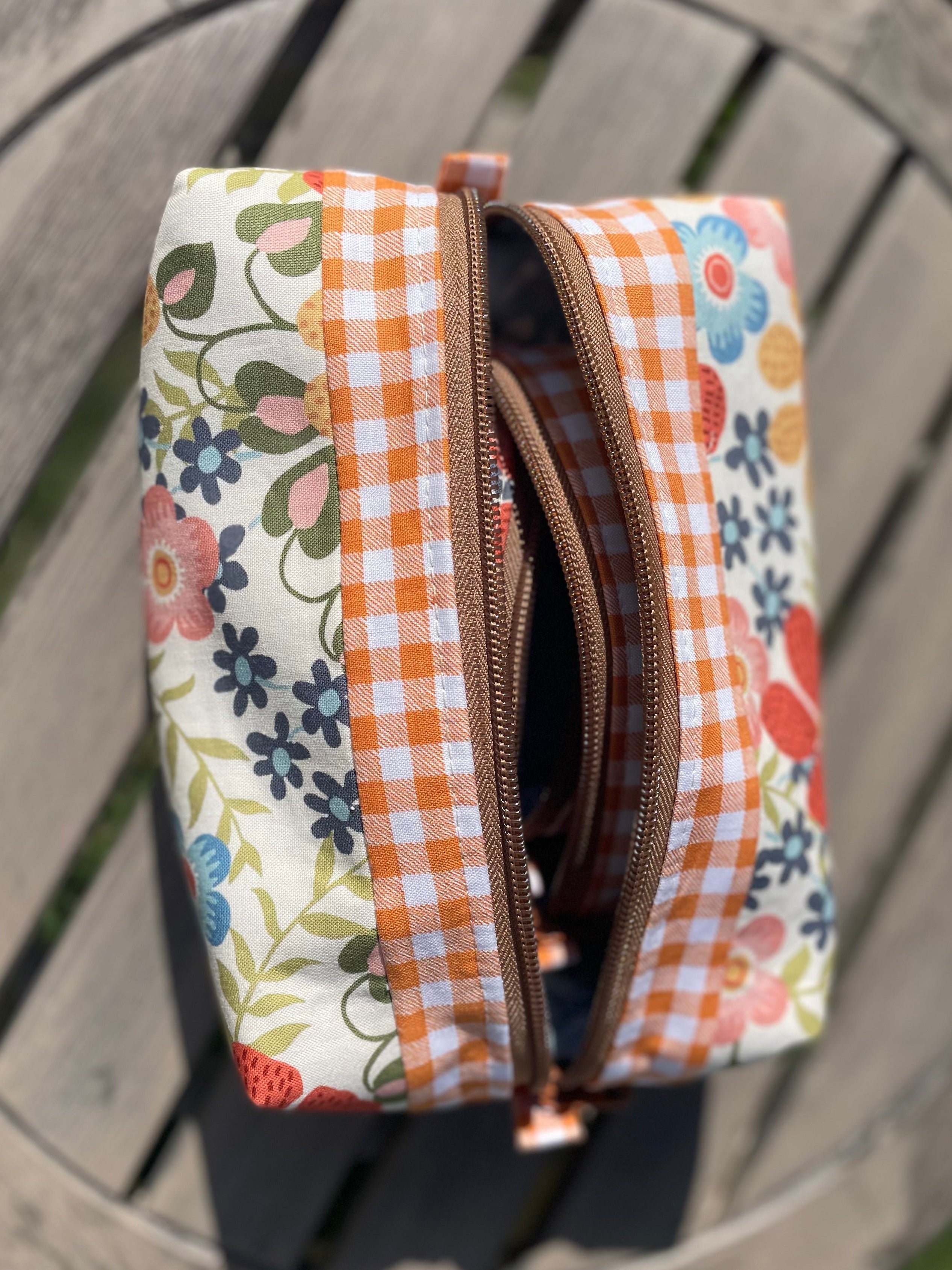 Fabric pouch with floral and checkered patterns on a wooden surface