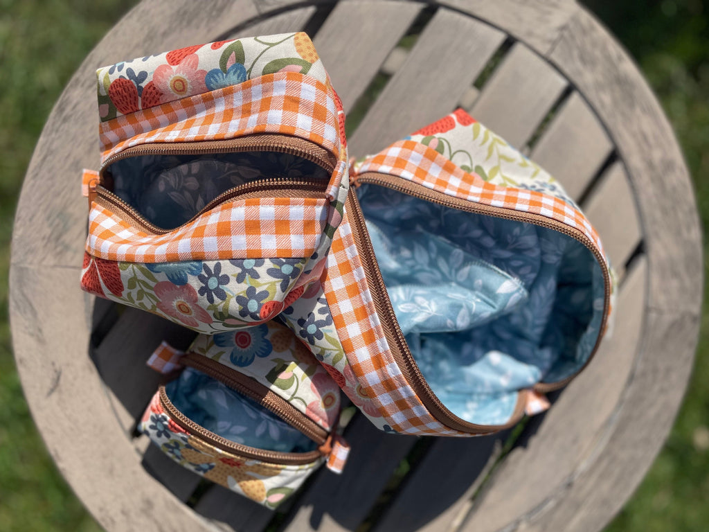 Three small fabric bags with floral and checkered patterns on a wooden surface.