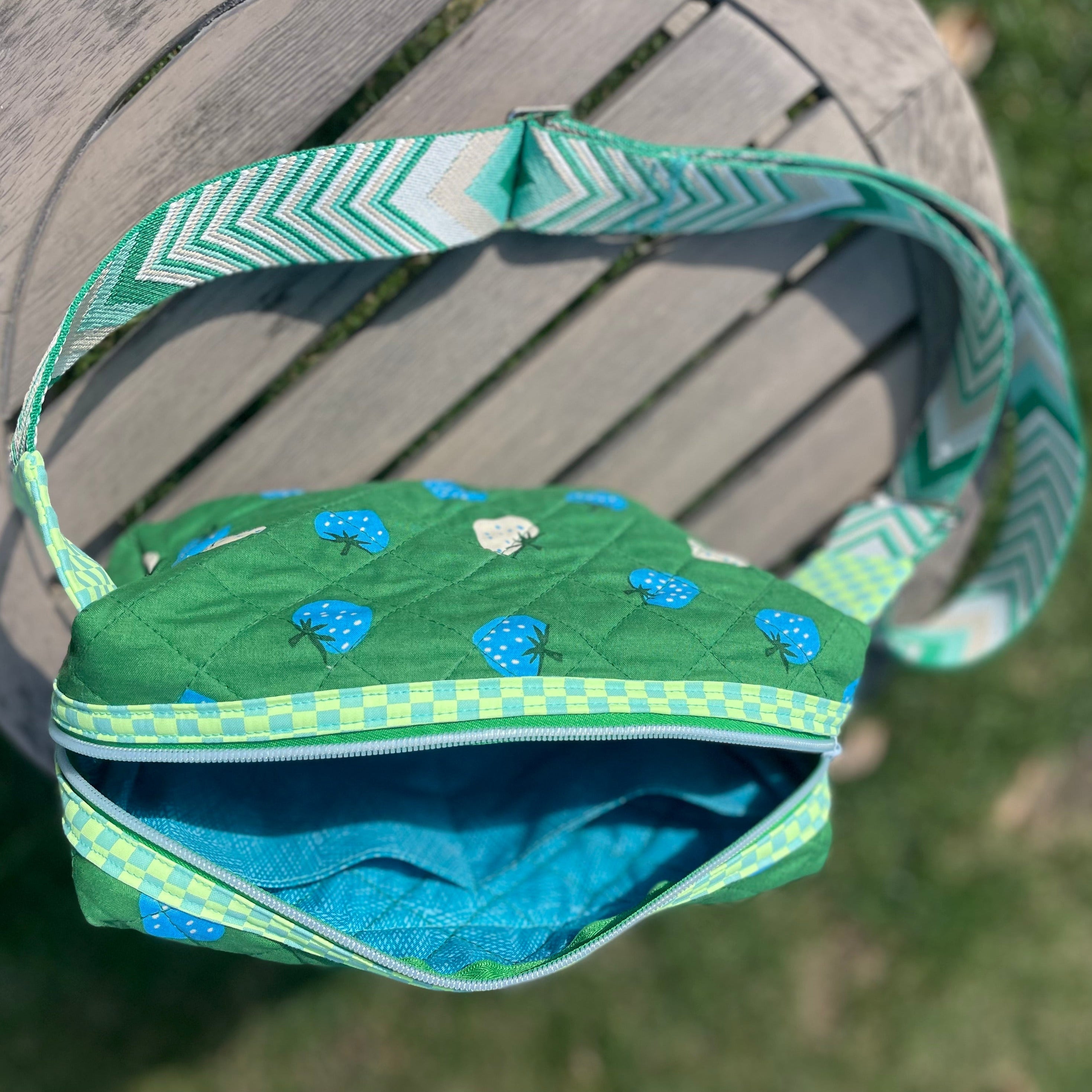 Green bag with blue floral pattern on a wooden surface outdoors