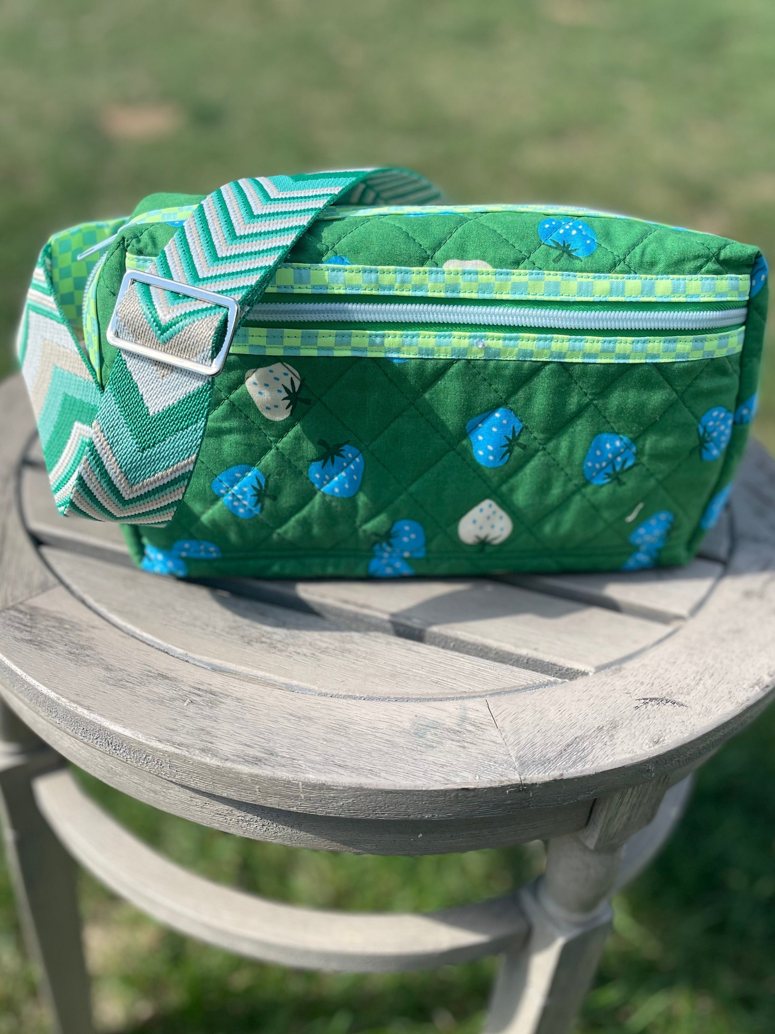 Green fabric bag with blue patterns on a wooden stool outdoors