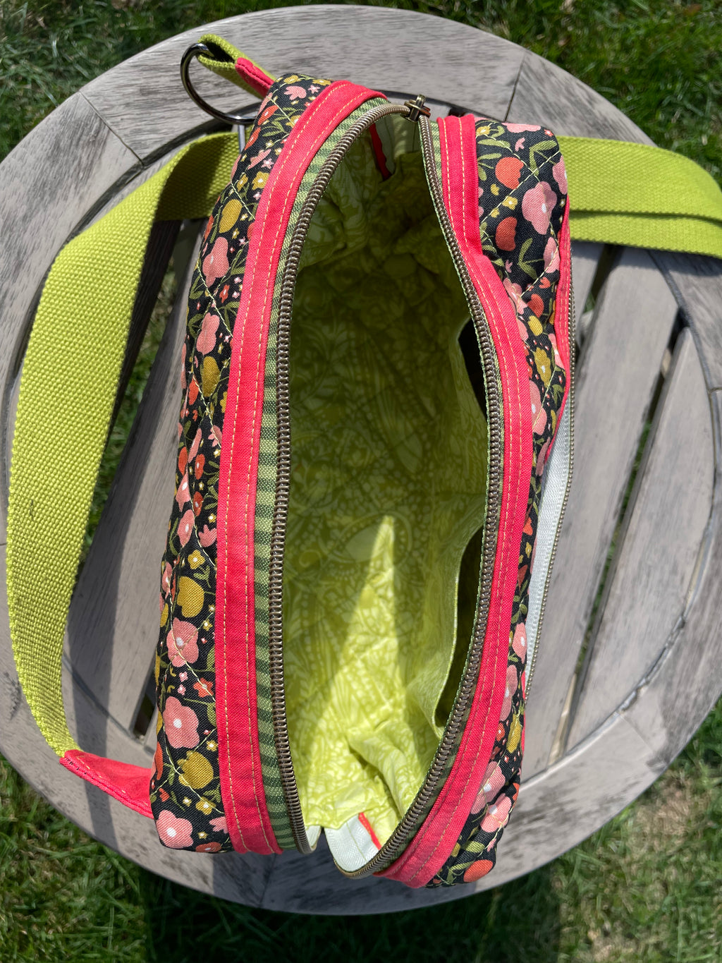 Open green bag with floral patterned zipper on a wooden surface