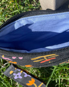 Black pouch with colorful strap on grass