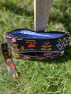 Floral-patterned pouch with a blue interior on a grassy background