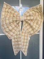 Beige checkered bow attached to a door with 'No Soliciting' sign.