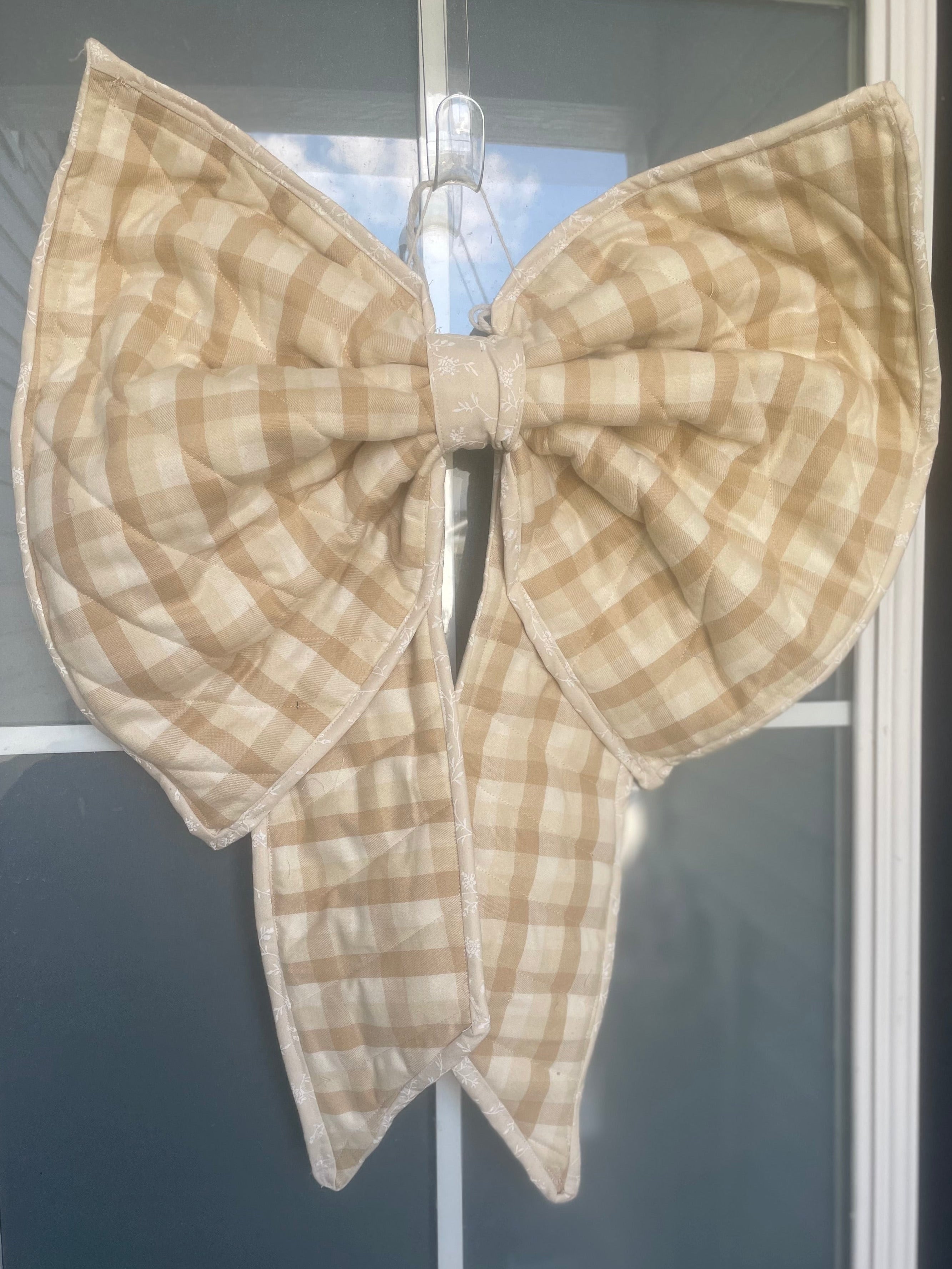 Beige checkered bow attached to a door with 'No Soliciting' sign.