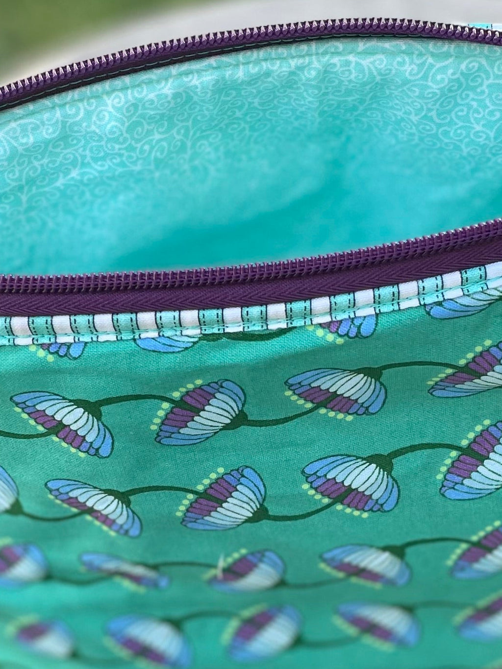 Green fabric pouch with a zipper on a wooden stool outdoors