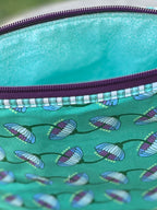 Green fabric pouch with a zipper on a wooden stool outdoors