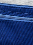 Blue corduroy pouch with a wrist strap on a wooden surface