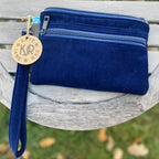Navy blue wallet with gold clasp on a wooden surface outdoors