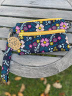 Floral patterned pouch with a yellow zipper on a wooden surface