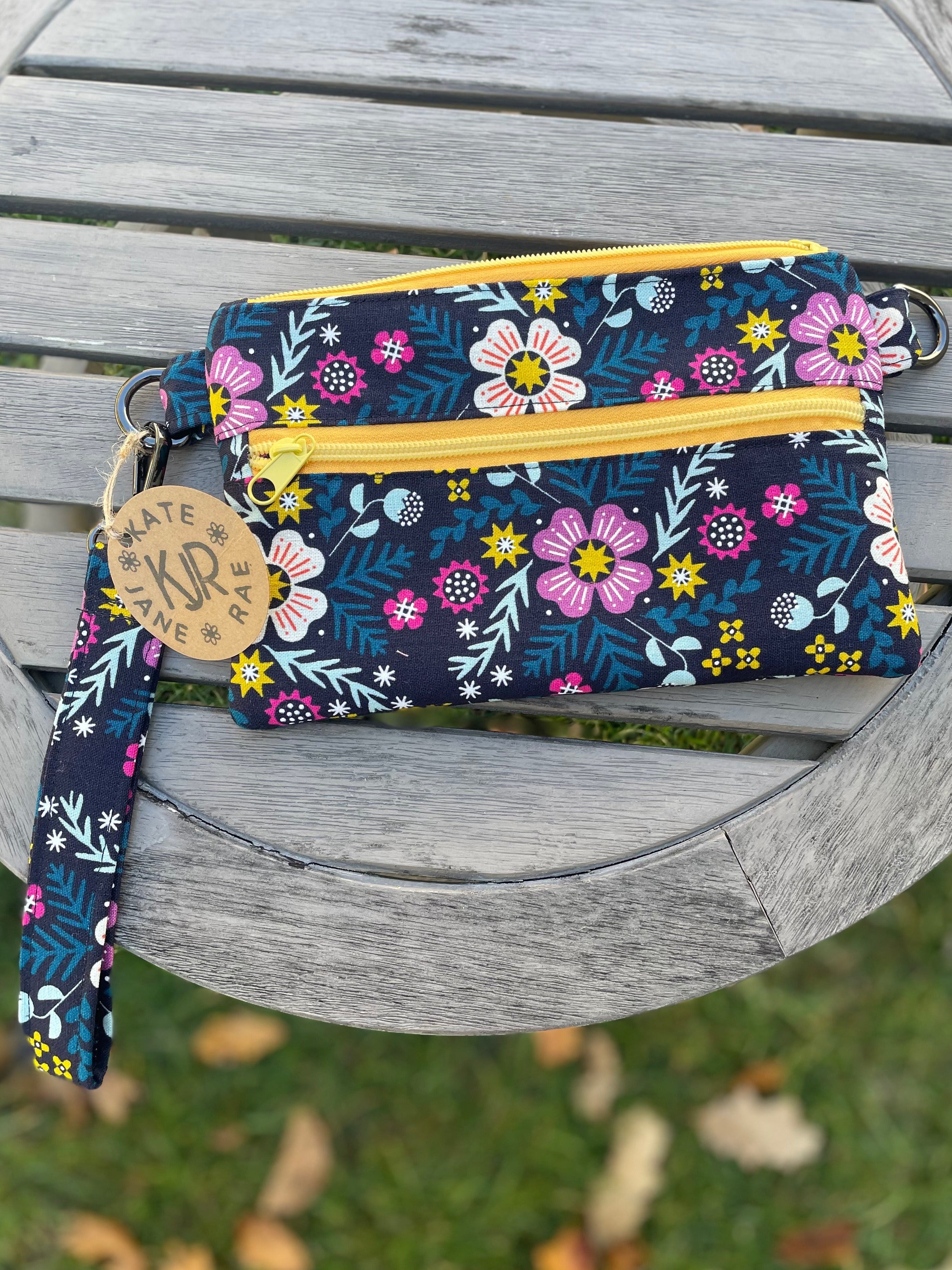 Floral patterned pouch with a yellow zipper on a wooden surface