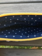 Close-up of a navy pouch with yellow zipper on a wooden surface