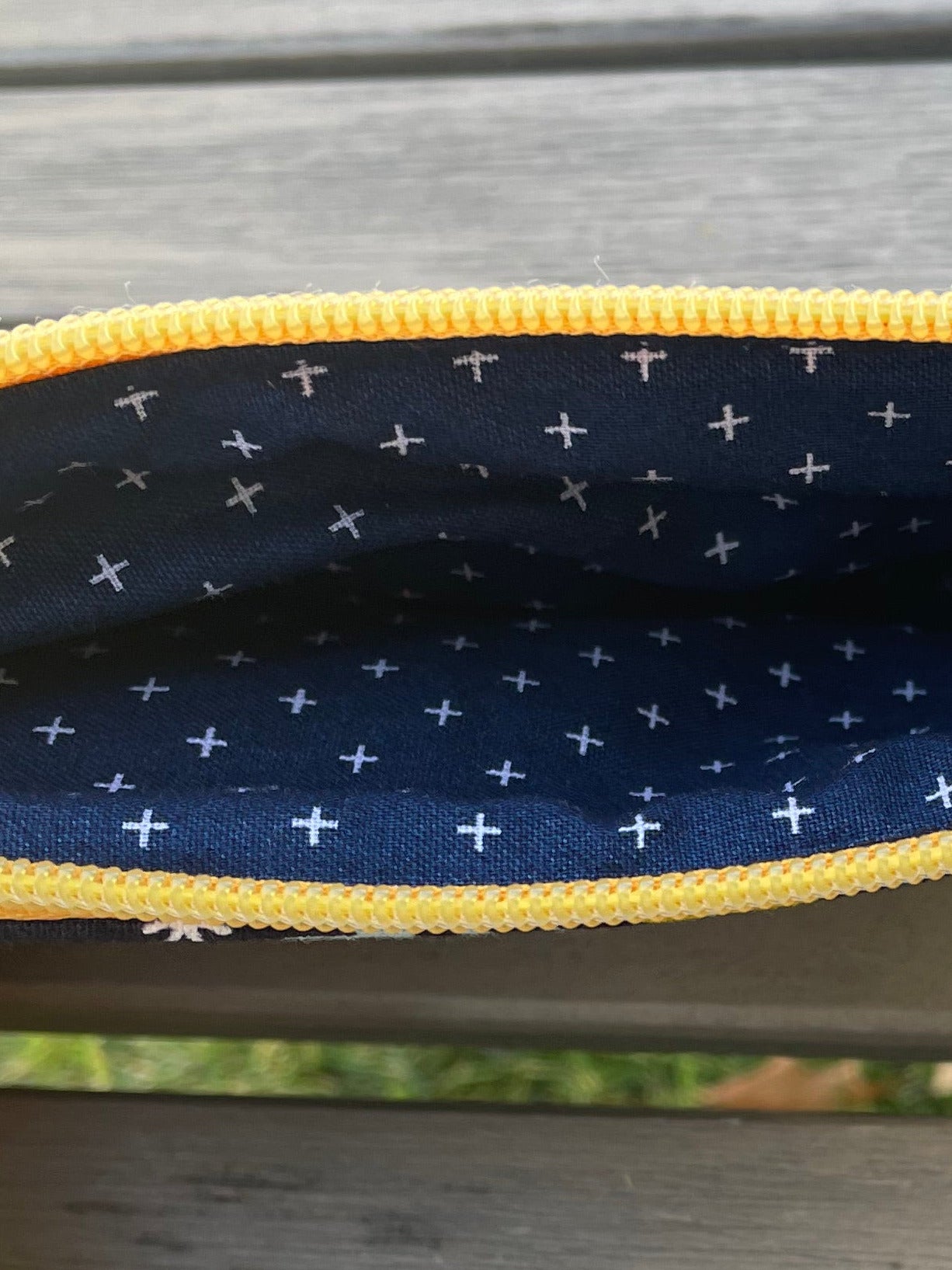 Close-up of a navy pouch with yellow zipper on a wooden surface