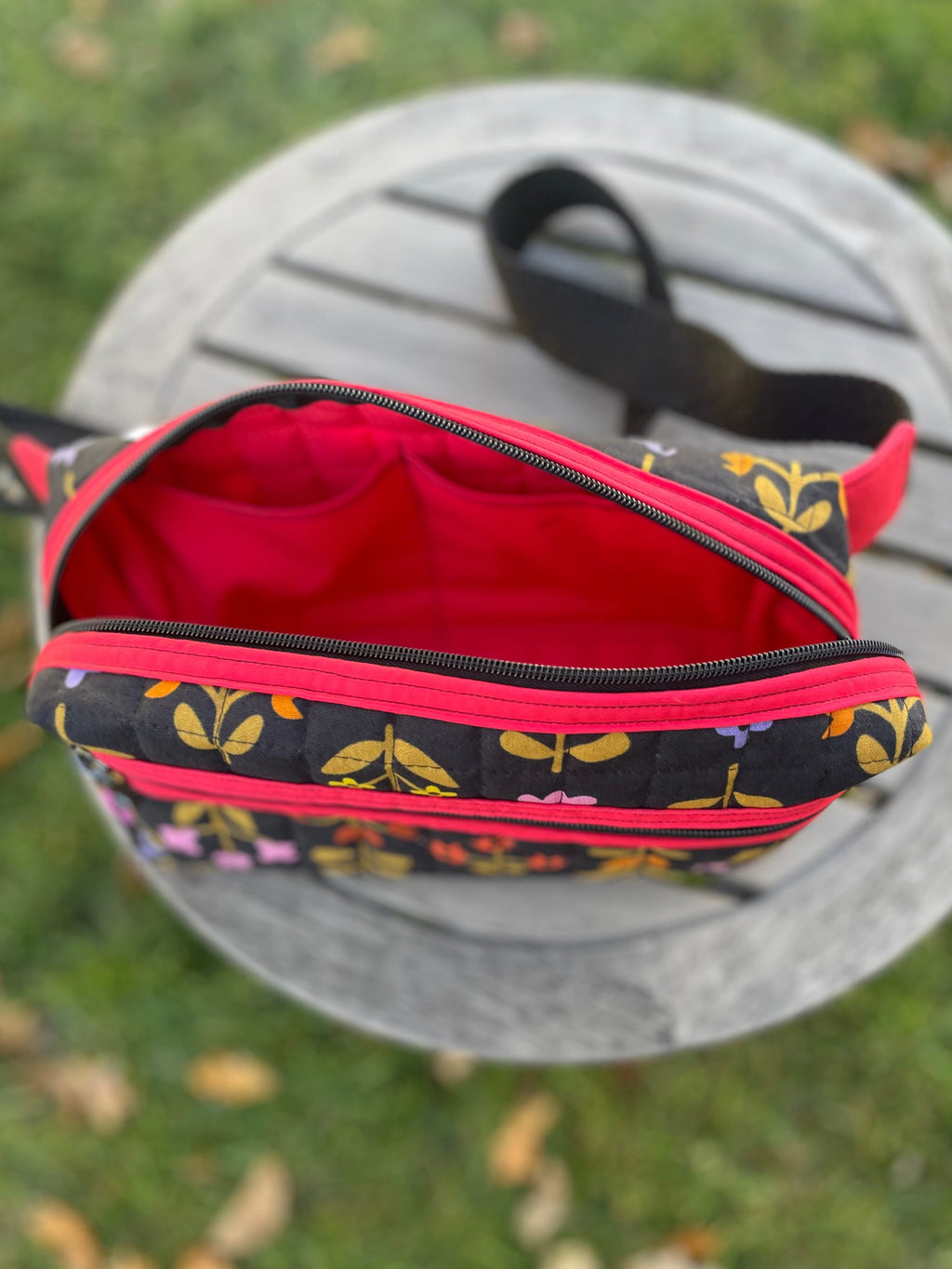 Floral-patterned pouch with red interior on a metal surface outdoors