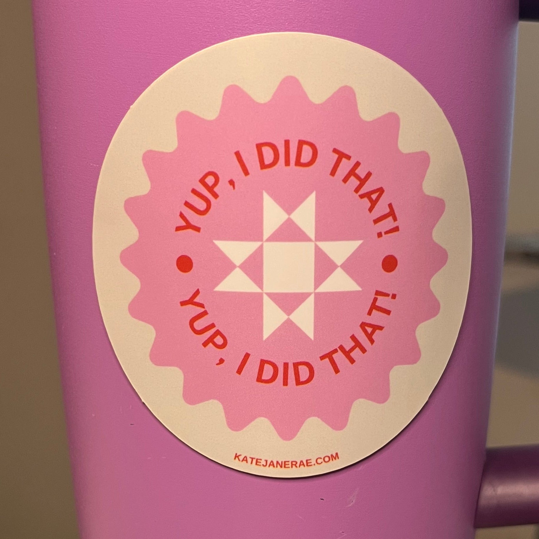 Pink water bottle with a circular design and text on a blurred background